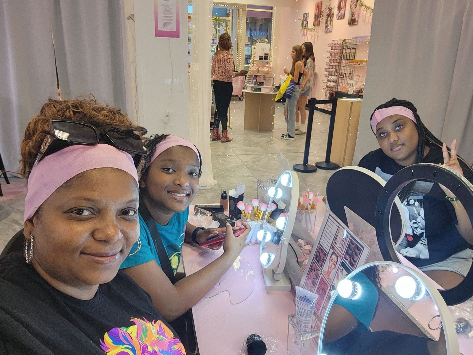 Five people lying on a bed with their legs raised. They wear white shirts, in a bright room with flowers.