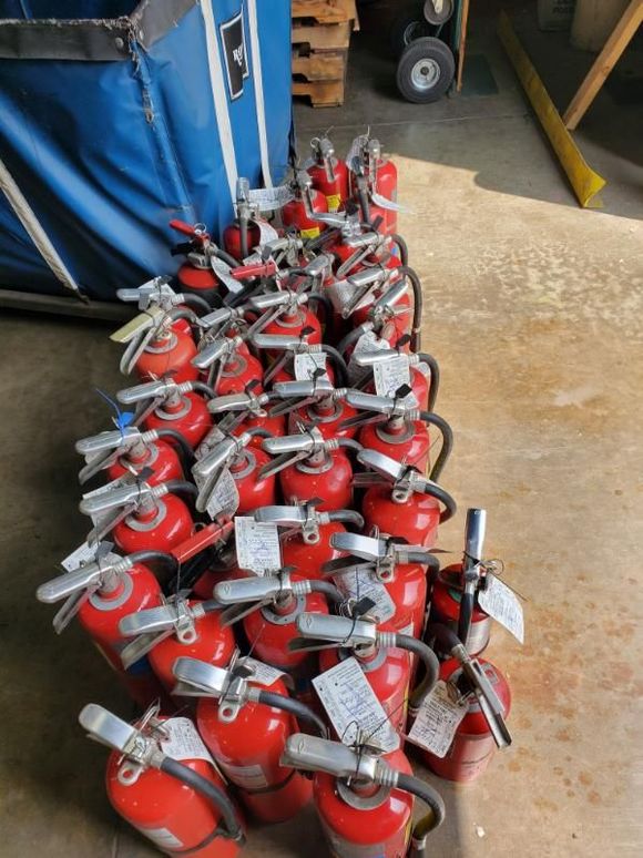 Person inspecting fire extinguishers in a red fire safety system room.