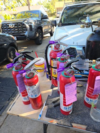 Person using a red fire extinguisher to put out a fire outdoors.