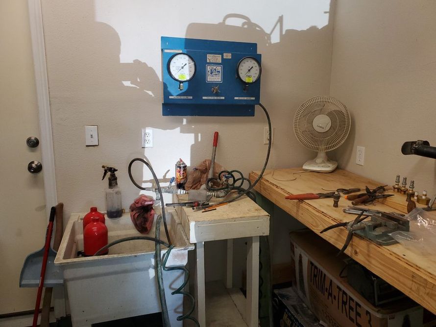 Fire extinguishers being inspected by a person in blue work clothes holding a clipboard.
