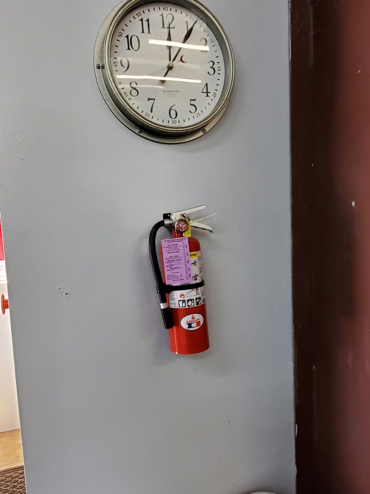 Red fire extinguisher mounted on a concrete column; night setting with city lights blurred in background.
