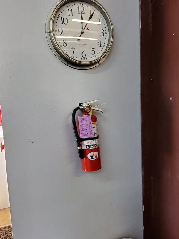 Red fire extinguisher mounted on a concrete column; night setting with city lights blurred in background.