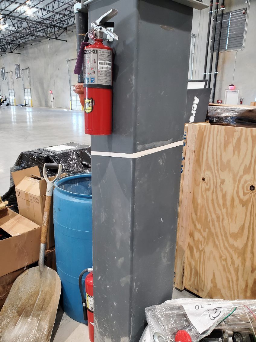 Person using fire extinguisher on fire in outdoor setting.