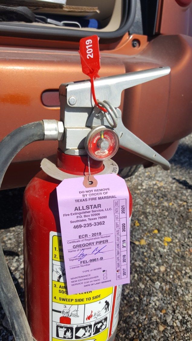 A person uses a red fire extinguisher to put out a fire outdoors.