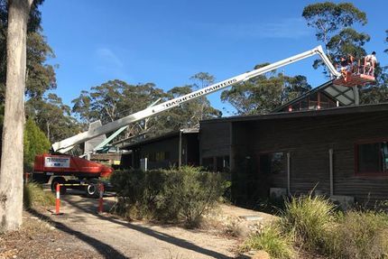 A crane is working on the roof of a house.