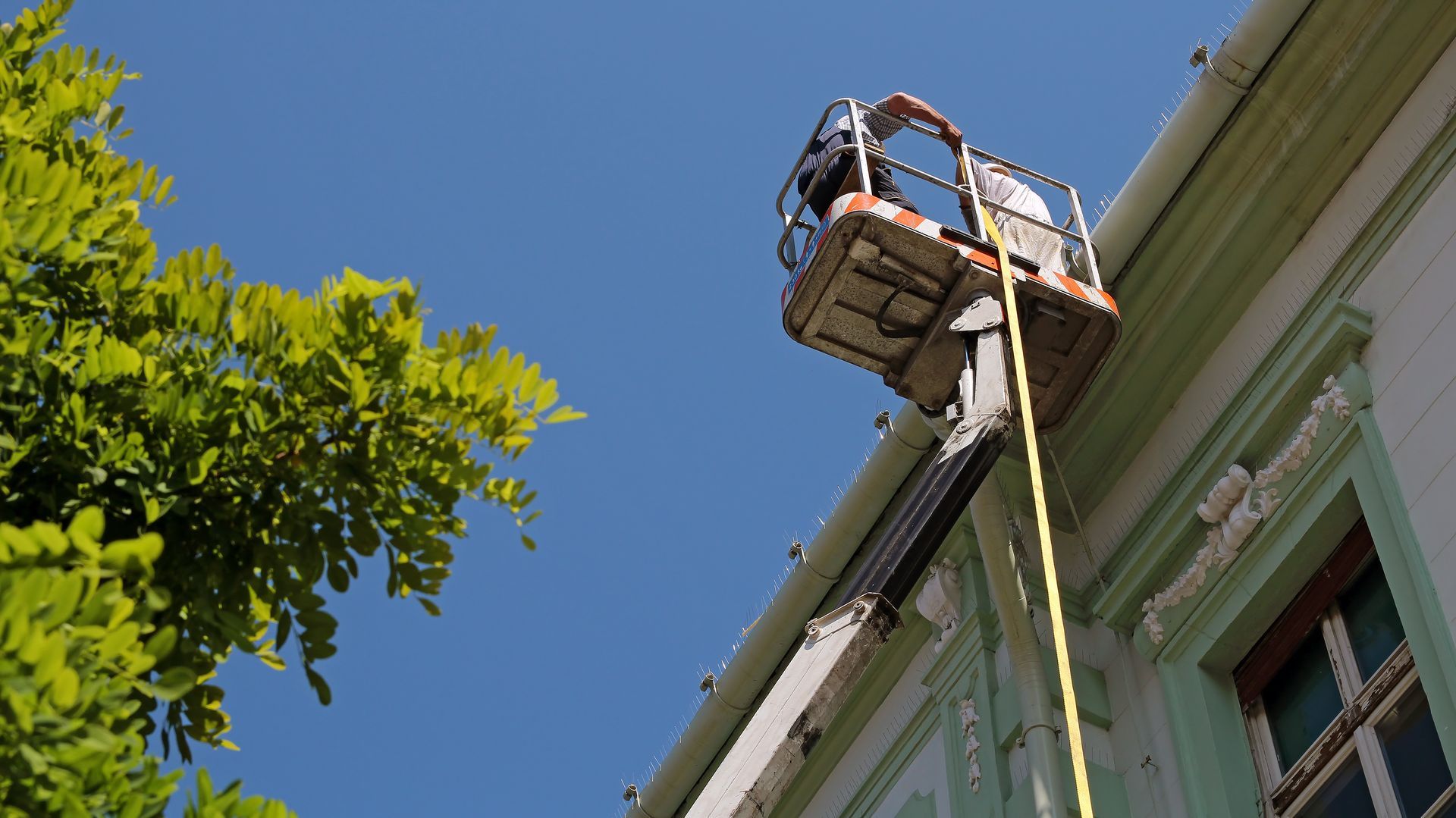 A man is working on the roof of a building with a crane.