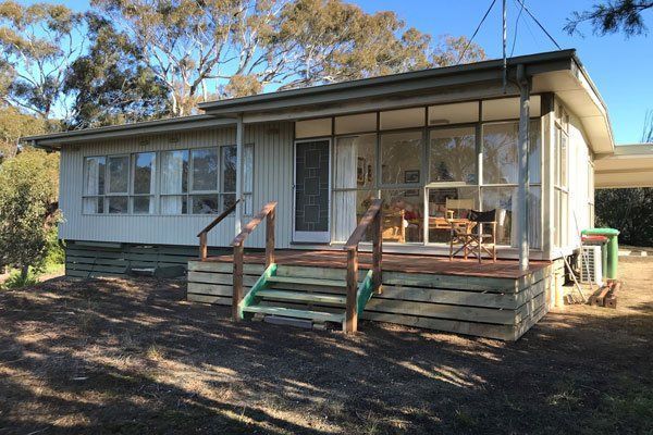 A small white house with a wooden deck and stairs.