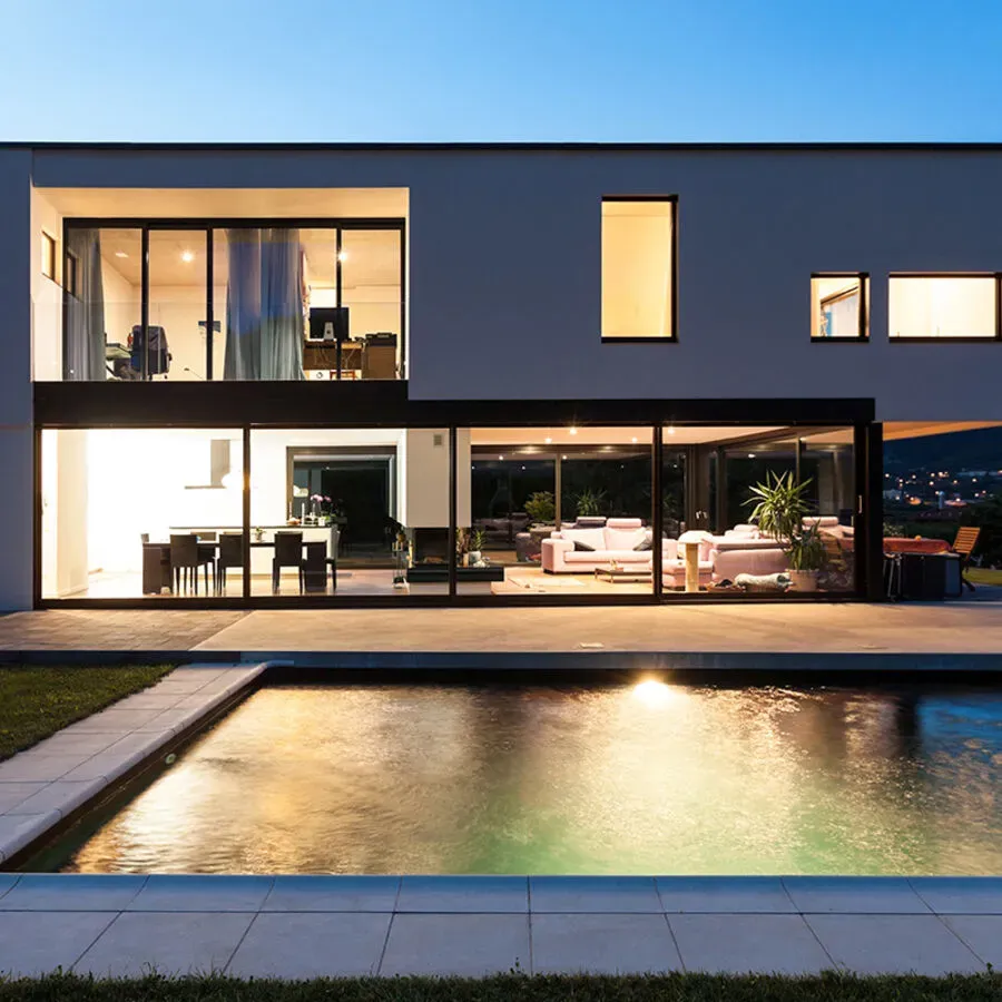 A modern house with a large swimming pool in front of it.