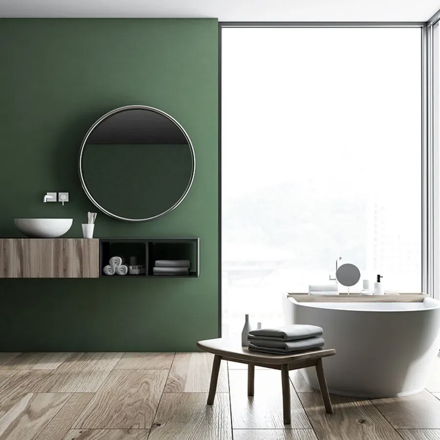 A bathroom with a tub , sink , mirror and green walls.