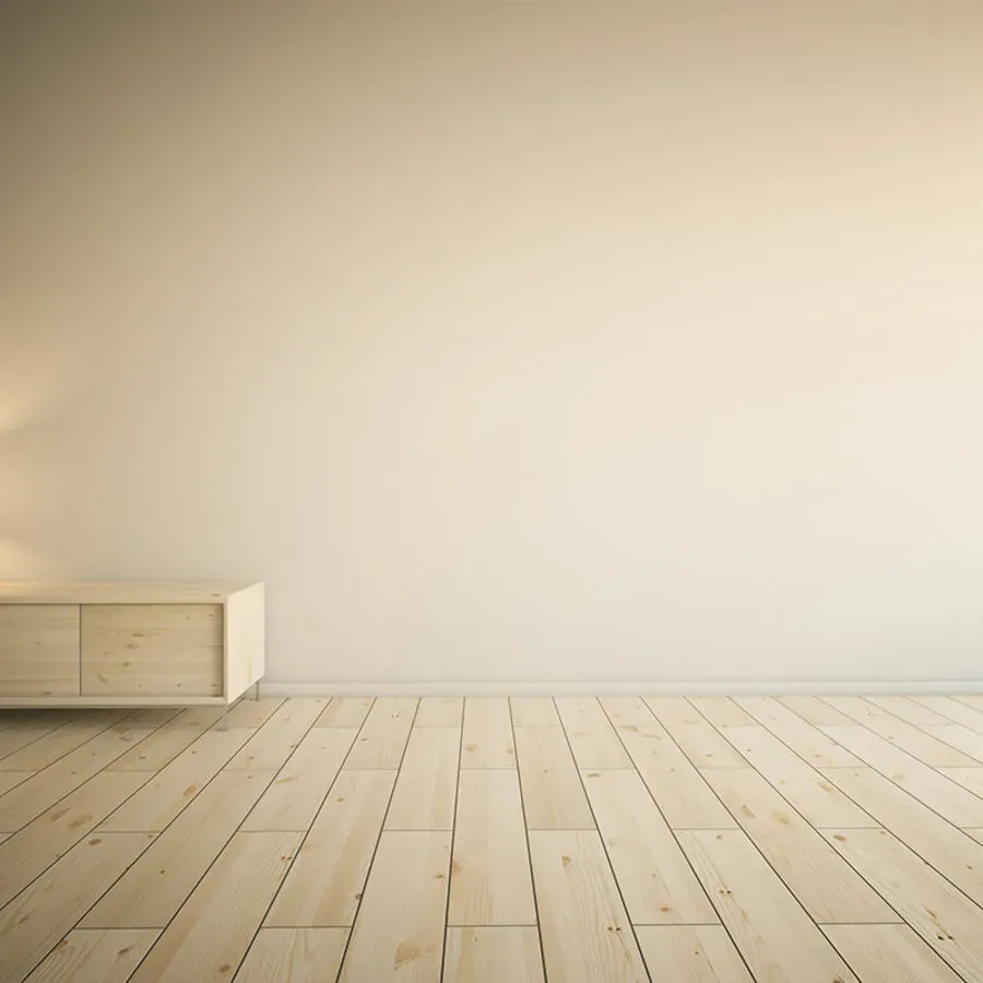 An empty room with a wooden floor and a white wall.