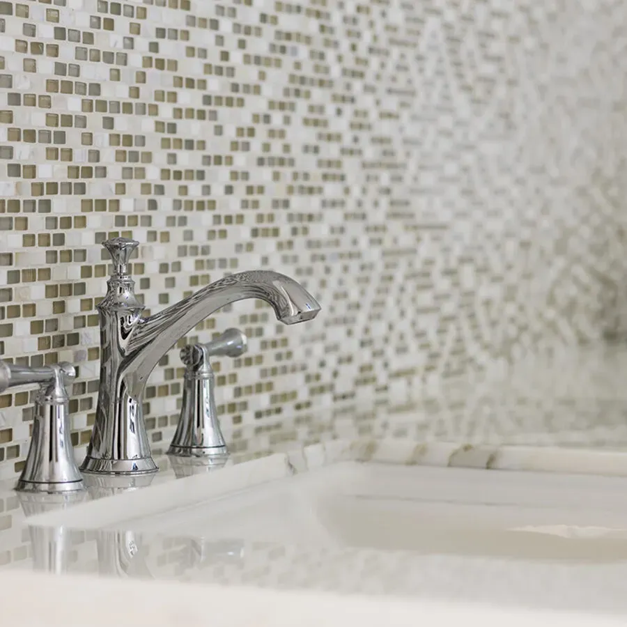 A bathroom sink with a faucet and a mosaic wall behind it.