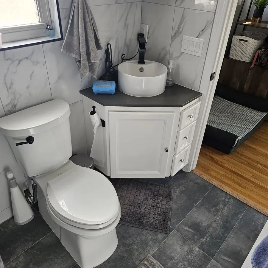 A bathroom with a toilet , sink , and cabinet.