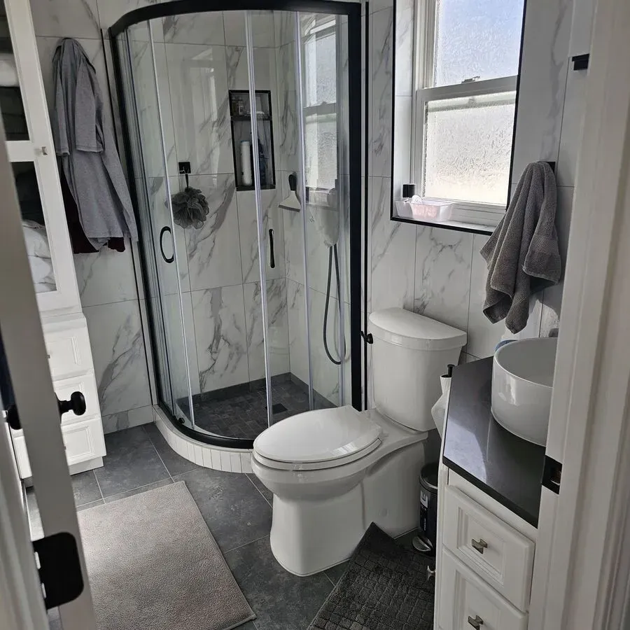 A bathroom with a toilet , sink , shower and window.