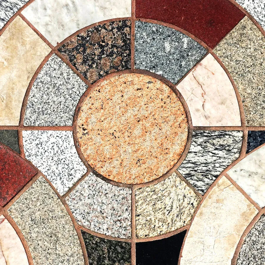 A circular pattern of different colored stones with a circle in the middle
