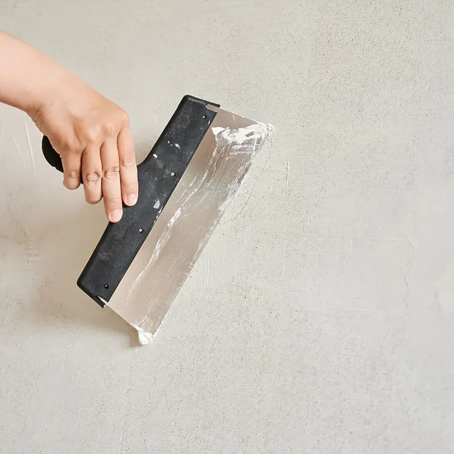 A person is plastering a wall with a spatula.