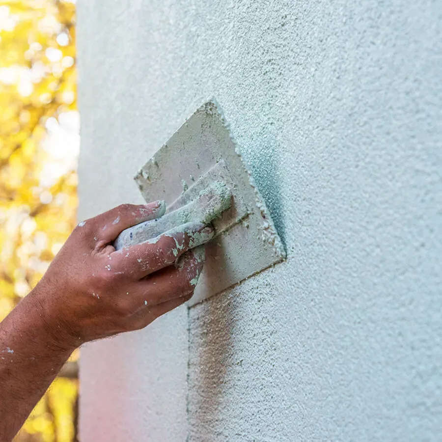A person is plastering a wall with a trowel.