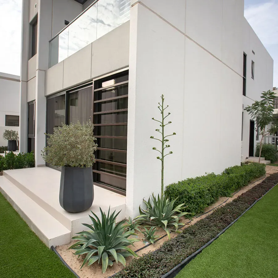 A white house with a black potted plant in front of it