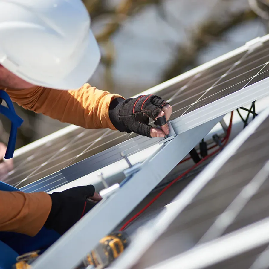 A man wearing a hard hat is working on a solar panel.
