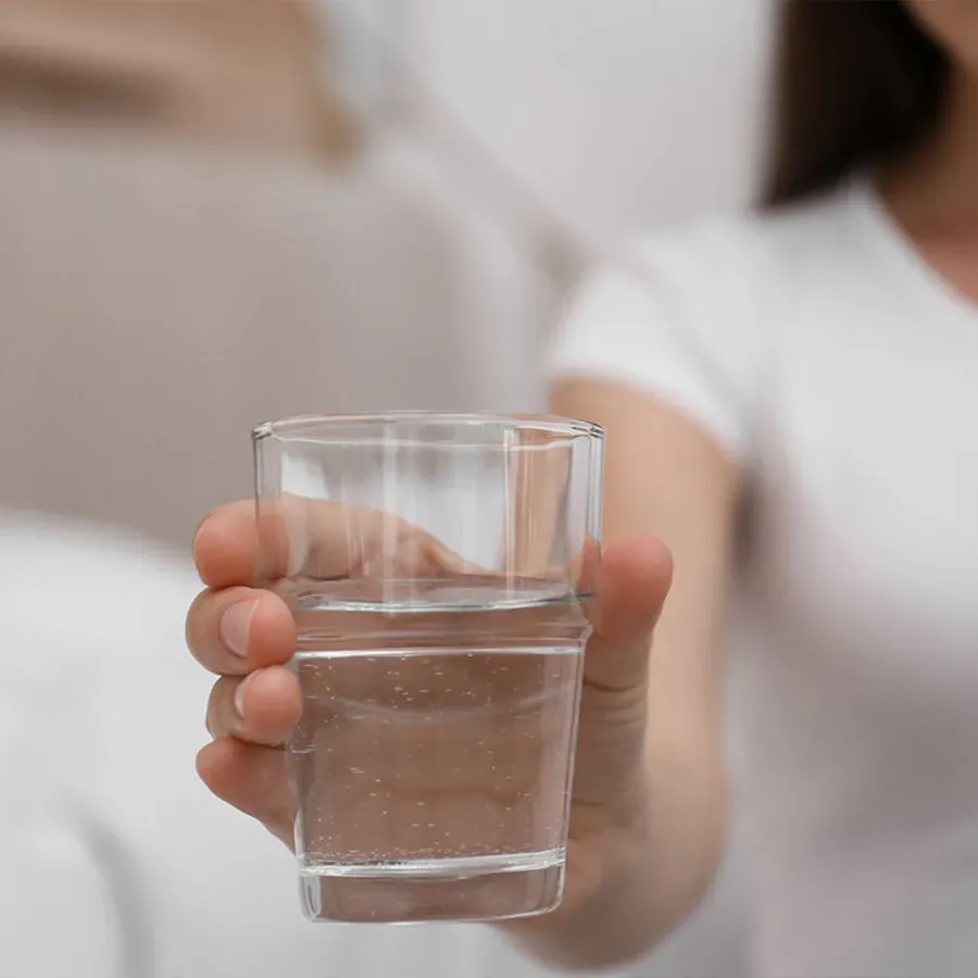 A woman is holding a glass of water in her hand.