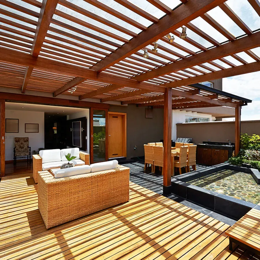 A wooden deck with wicker furniture under a pergola