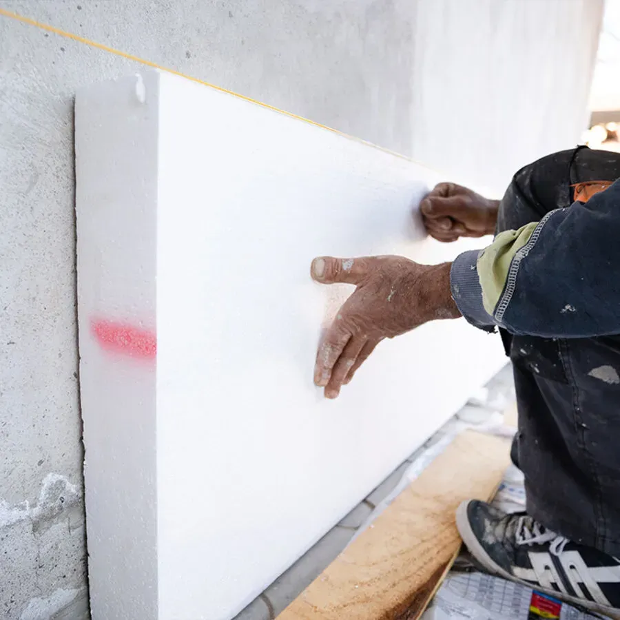 A man is pointing at a piece of styrofoam on a wall