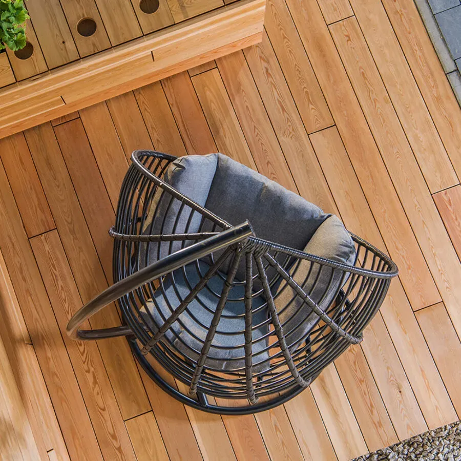 A wicker chair is sitting on a wooden deck.