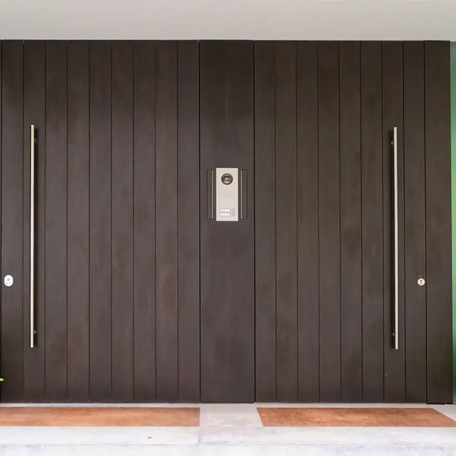A large wooden door with stainless steel handles and a doorbell.