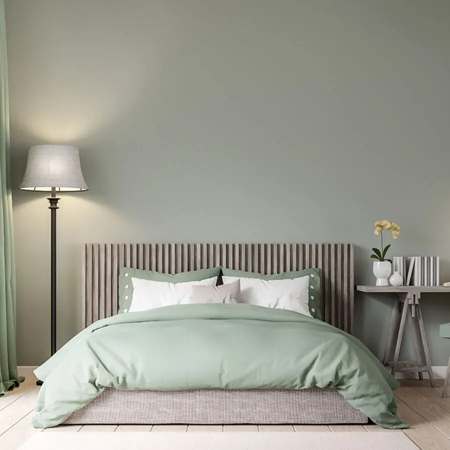 A bedroom with a bed , lamp , table and green walls.