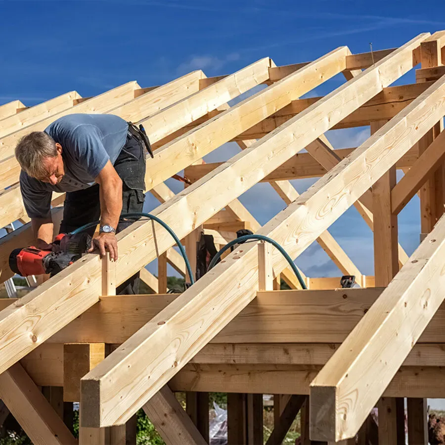 A man is working on a wooden structure with a drill.