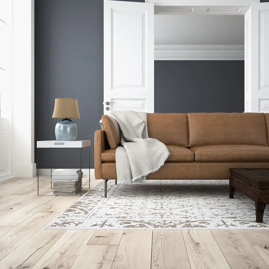 A living room with a brown leather couch and a rug.