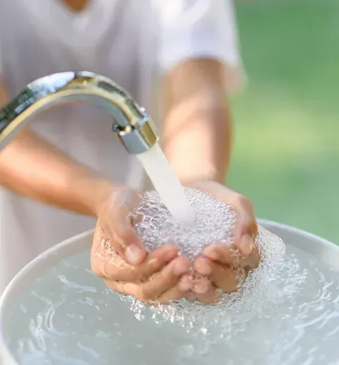 A person is washing their hands under a faucet.