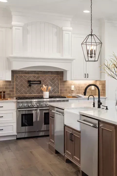 A kitchen with white cabinets , stainless steel appliances , a sink , and a stove.