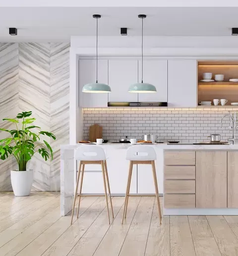A kitchen with white cabinets , wooden floors and stools.
