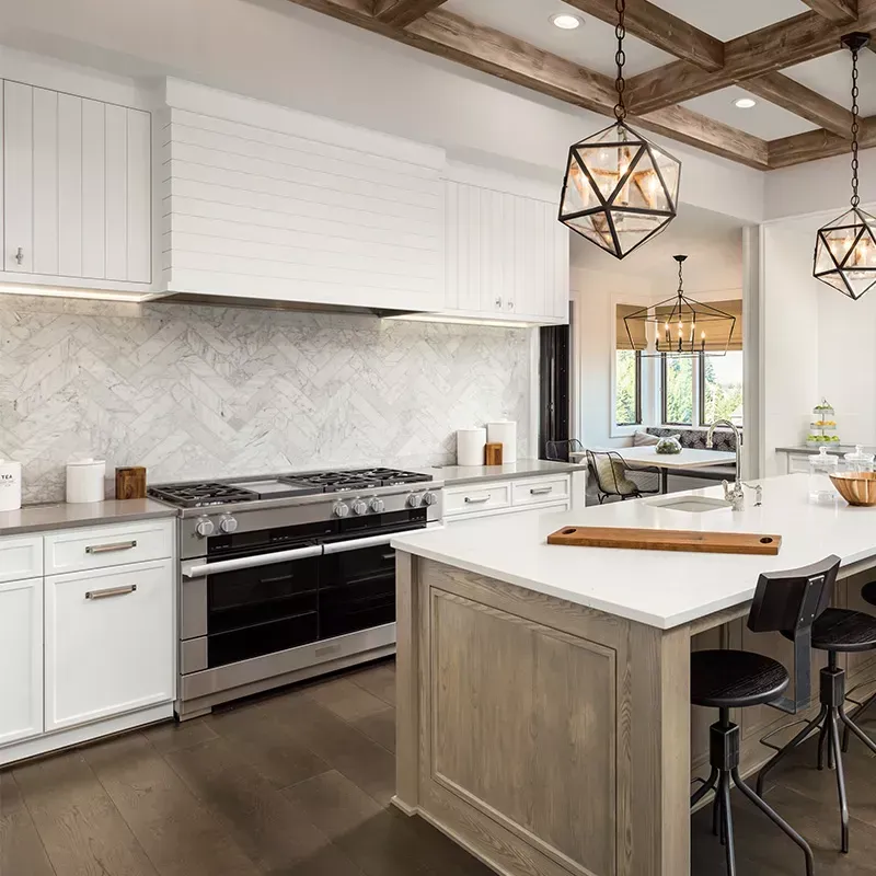 A kitchen with white cabinets , stainless steel appliances , a large island and a stove.