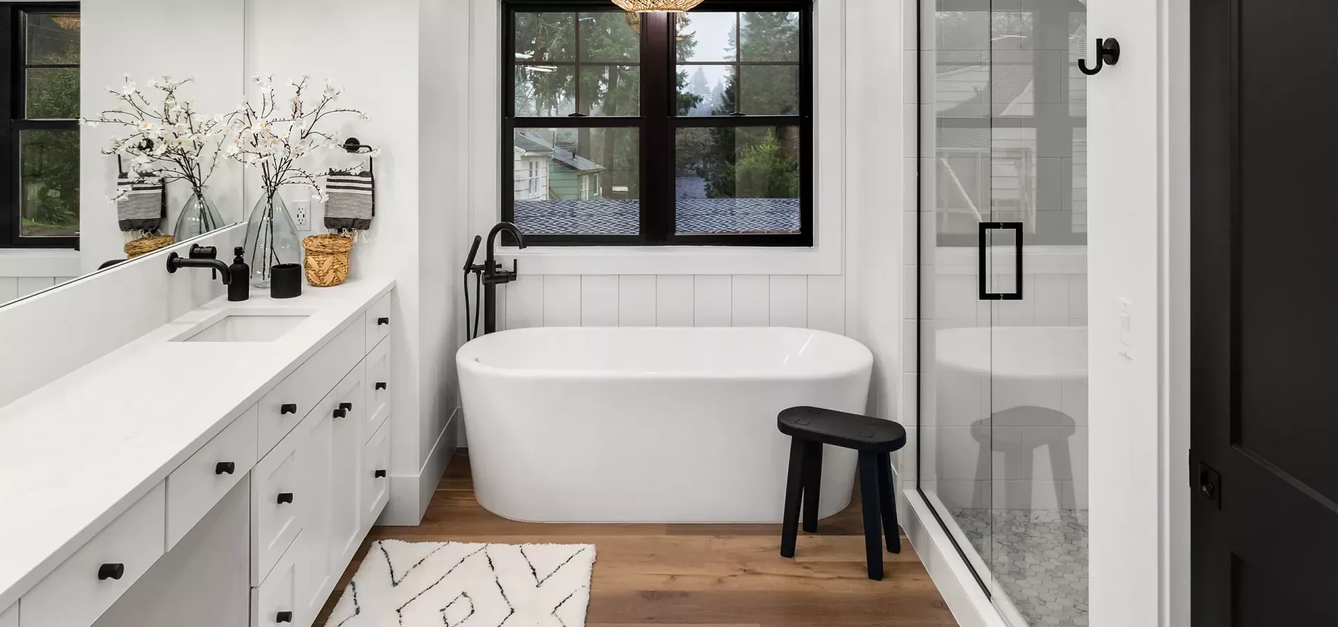 A bathroom with a tub , sink , mirror and window.