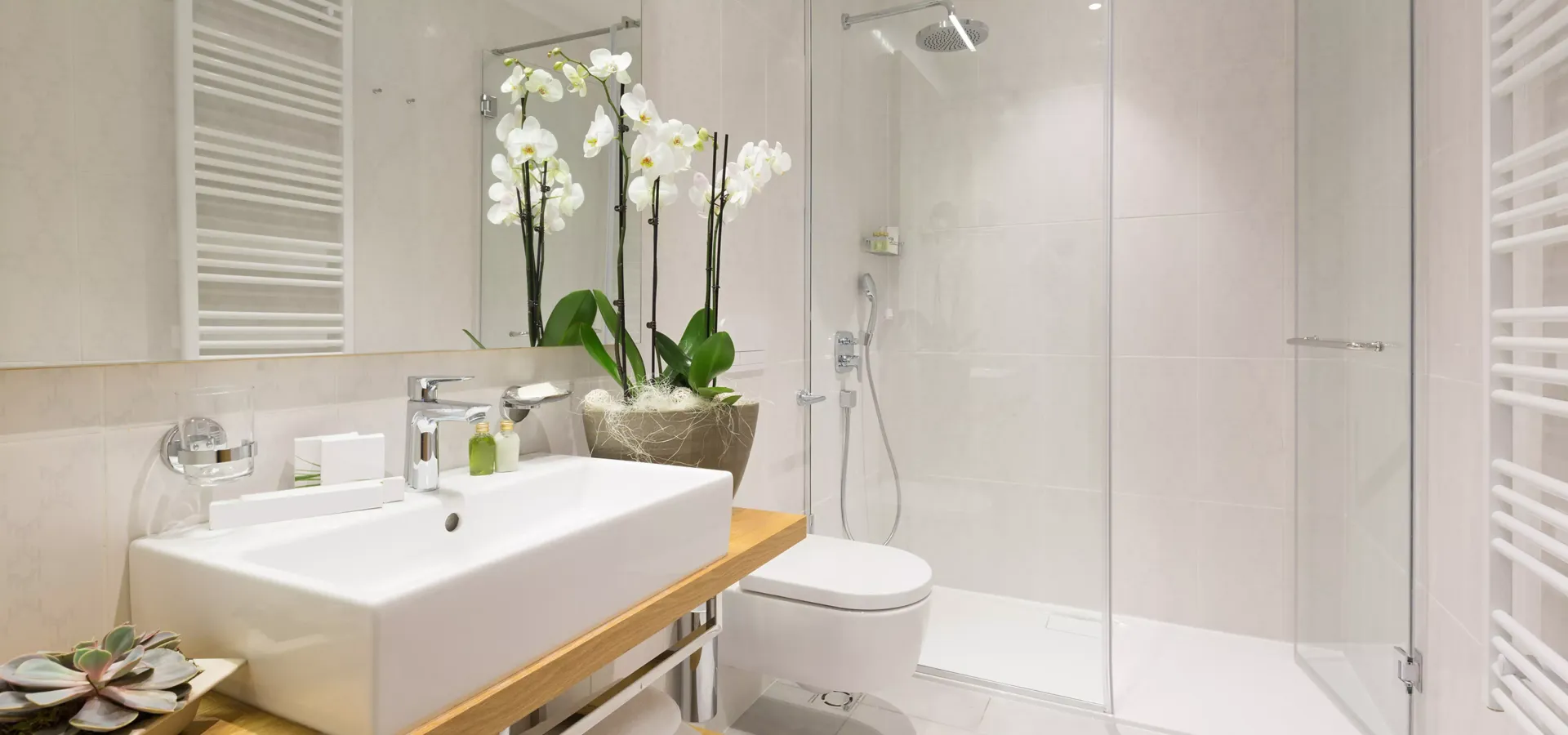 A bathroom with a sink , toilet , shower and mirror.