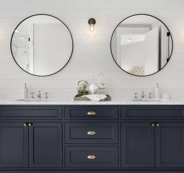 A bathroom with two sinks and two round mirrors.