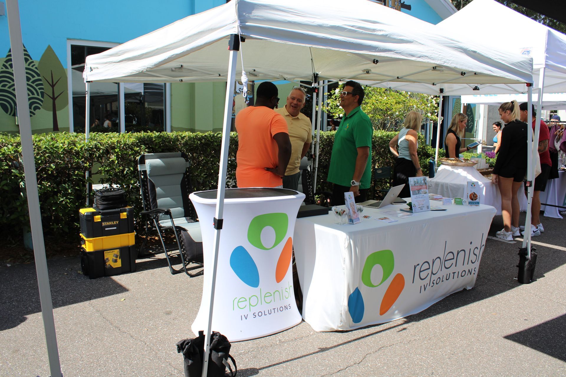 a group of people standing around a table under a tent that says redemic