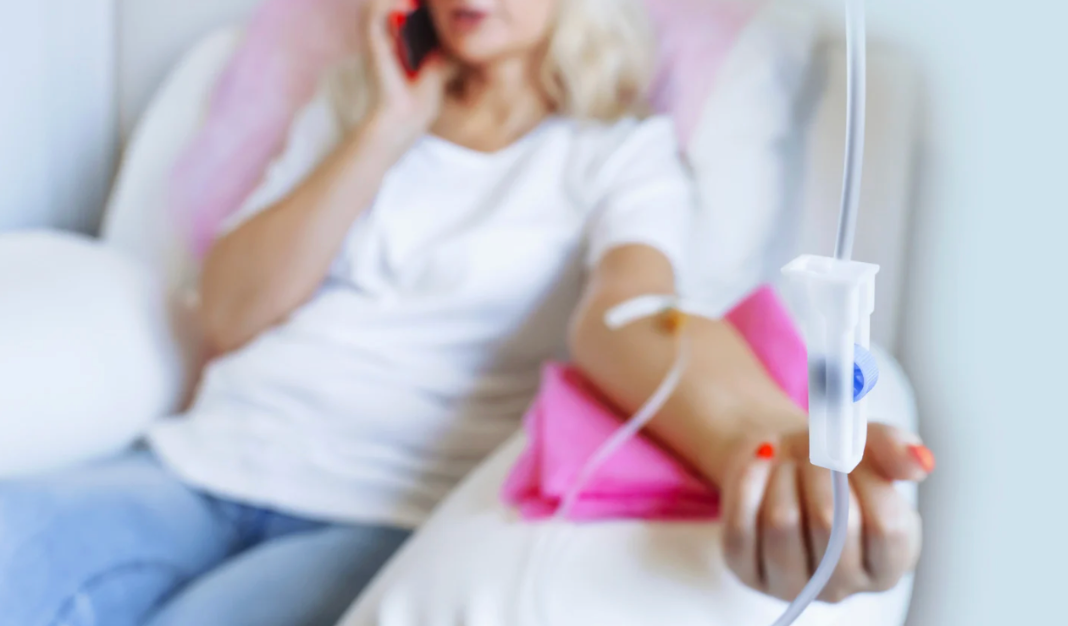 Woman receiving IV therapy treatment while seated comfortably and speaking on a mobile phone.