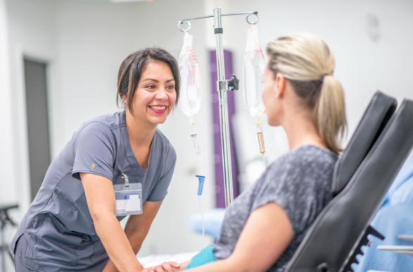 Medical professional smiling at her patient who is receiving IV therapy.