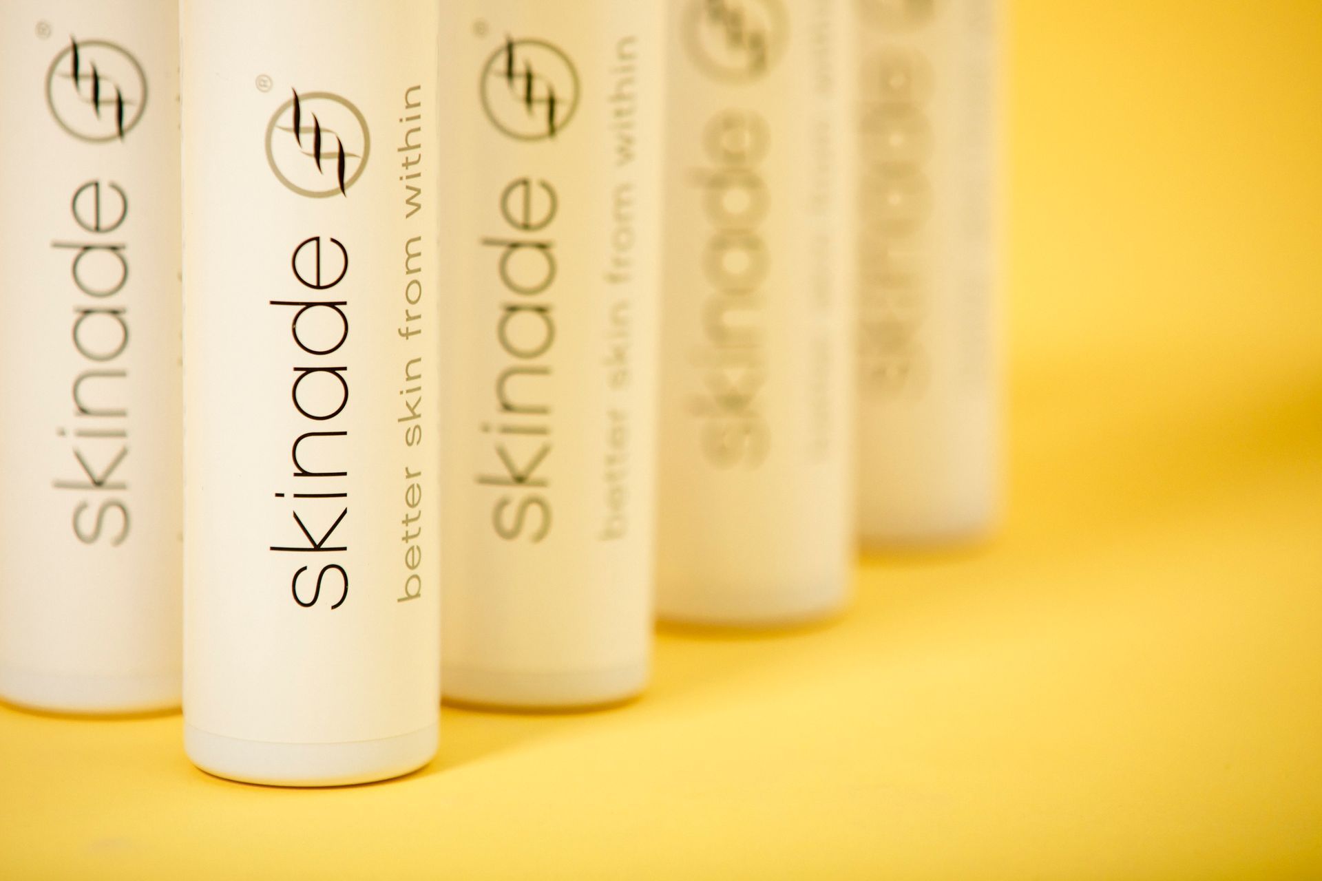 several bottles of skinade are lined up on a yellow surface