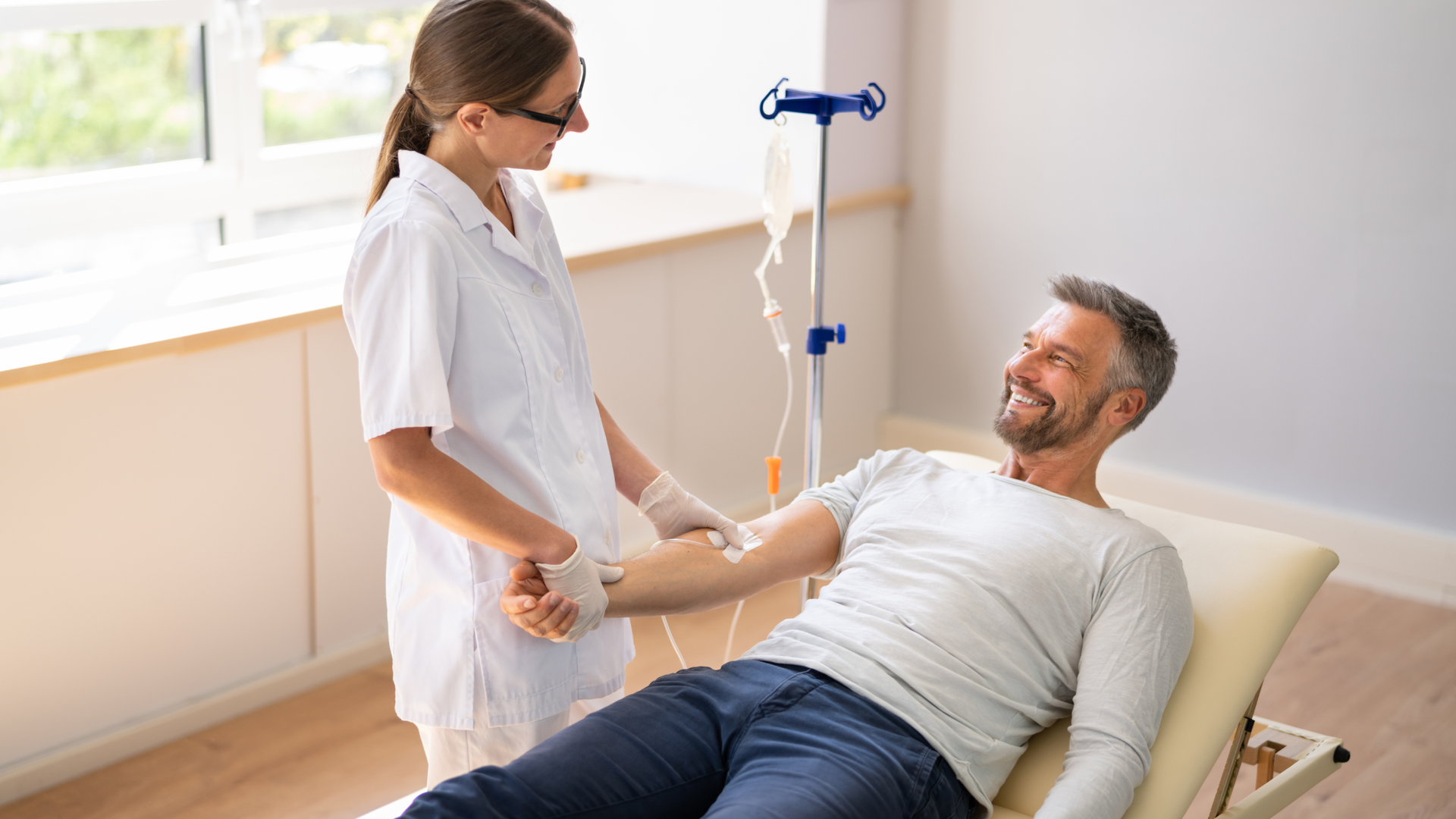 Nurse checking a smiling patient on a comforting chair with an IV drip nearby