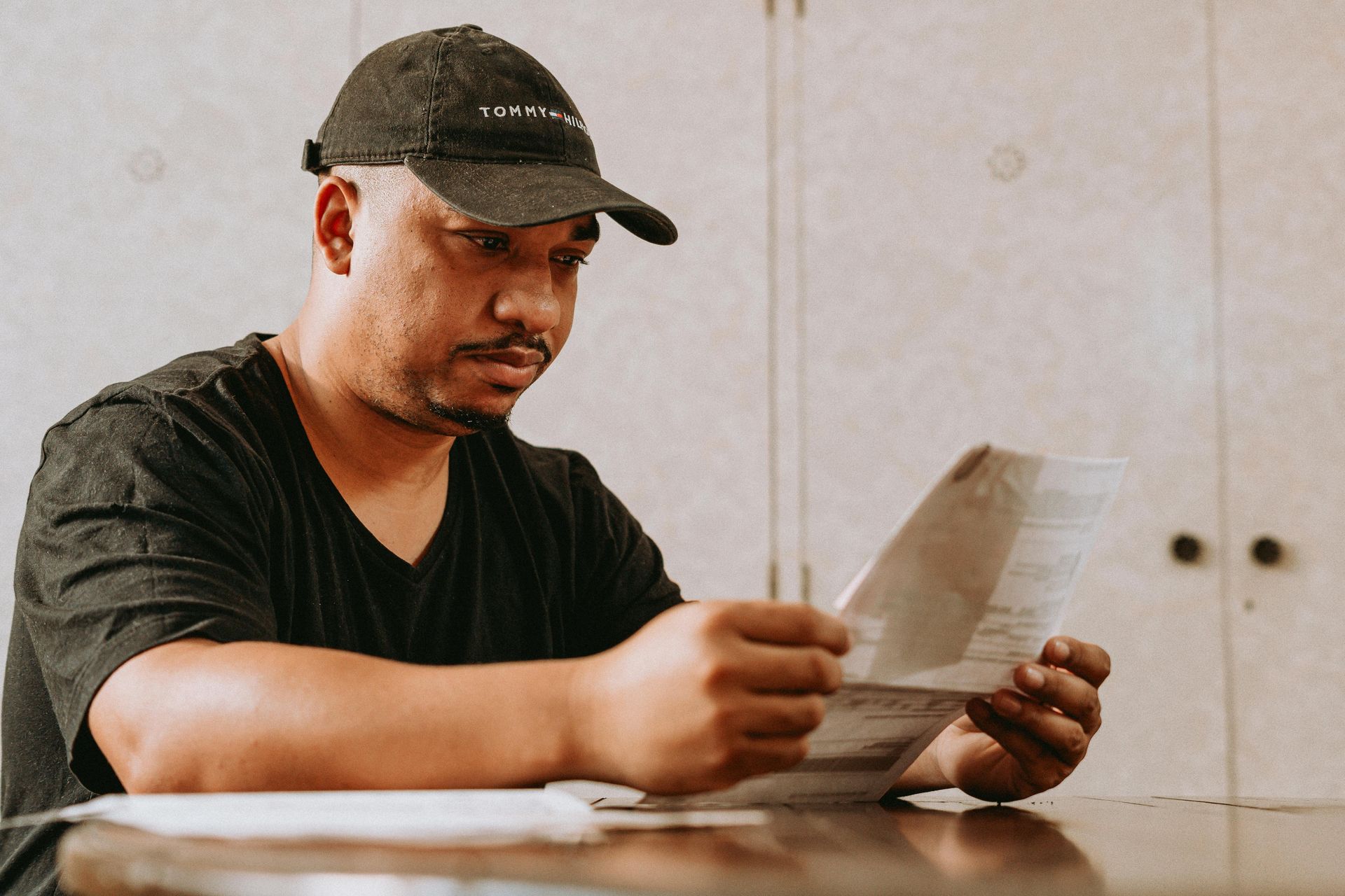 A man is sitting at a table reading a piece of paper.