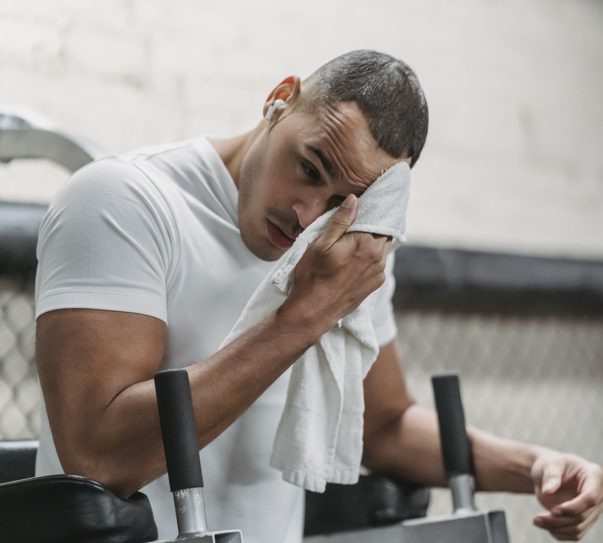 a man is wiping his face with a towel in a gym .