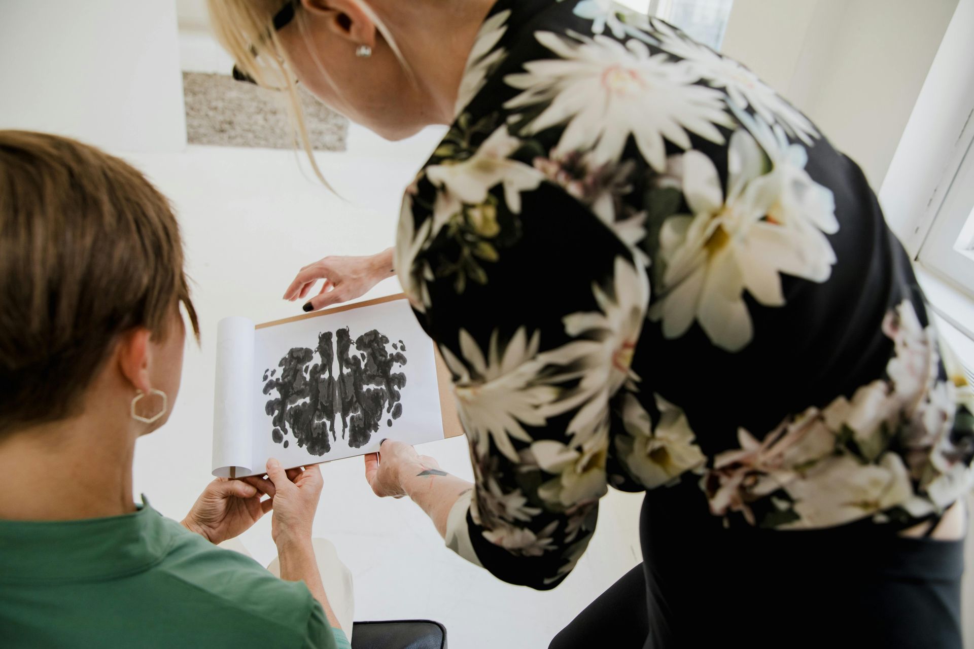 Two women are looking at a picture of a brain on a clipboard.