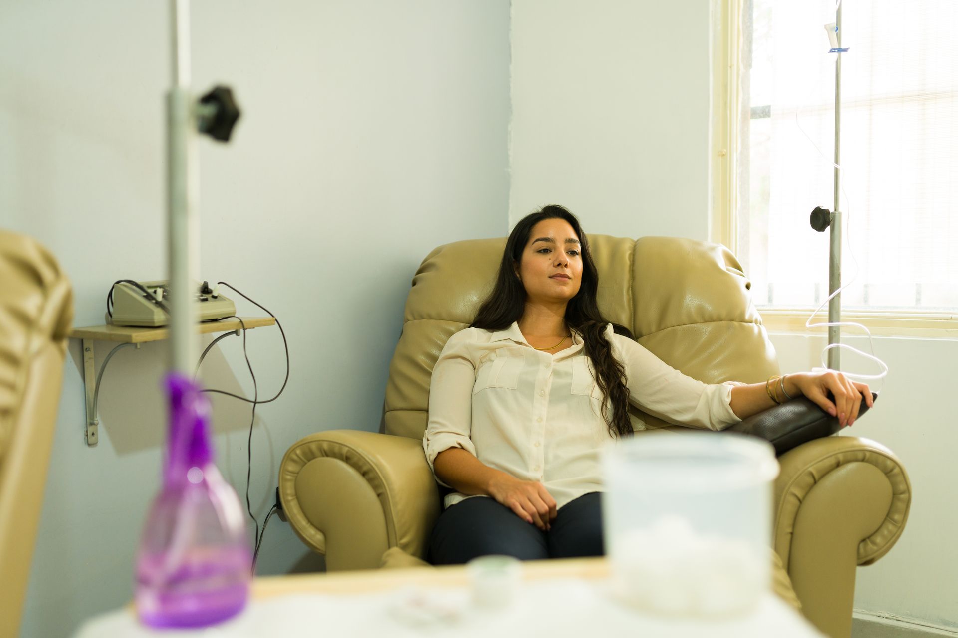 A woman is sitting in a chair with an iv in her hand.