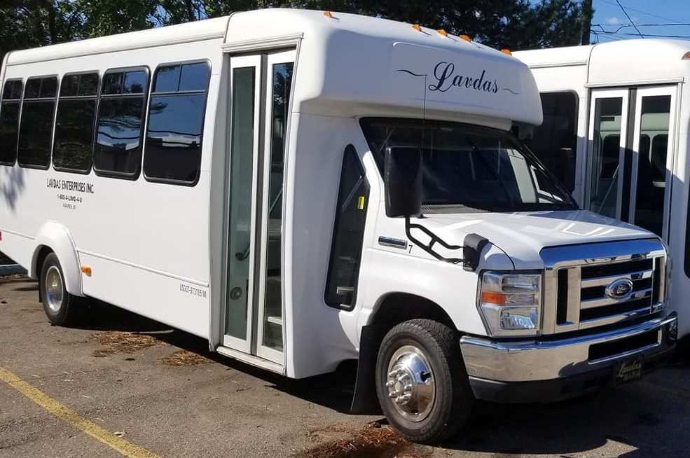 A white bus with the word landa on the front is parked in a parking lot
