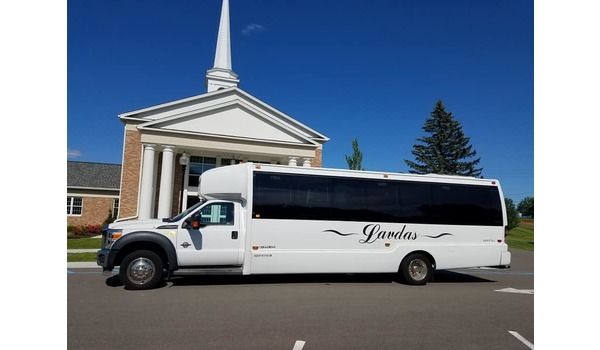 A white bus is parked in front of a church.