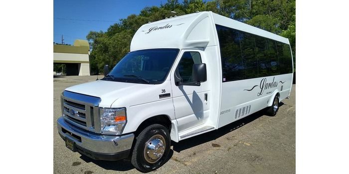 A white shuttle bus is parked in a parking lot.