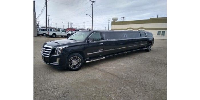 A black limousine is parked in front of a building.